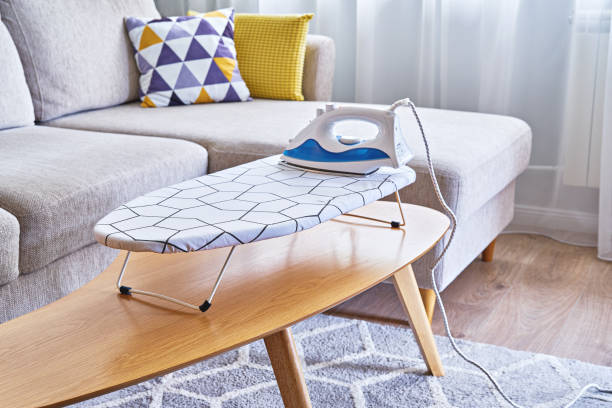 Iron for ironing on small tabletop ironing board in cozy and living room