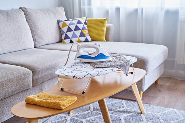istock Washed towels on table ironing board and an iron in a small living room with sofa 1335110429