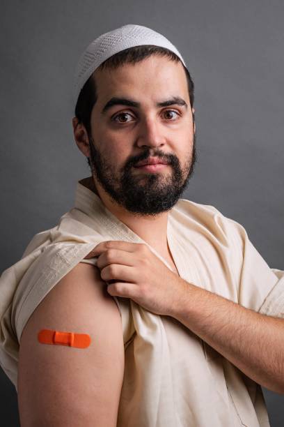 junger muslimischer mann posiert mit einem impfpflaster im arm - studio shot african descent minority looking at camera stock-fotos und bilder