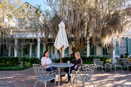 Two female tourists relaxing in the bricked courtyard at Myrtles Plantation, St. Francisville; Louisiana; USA;
