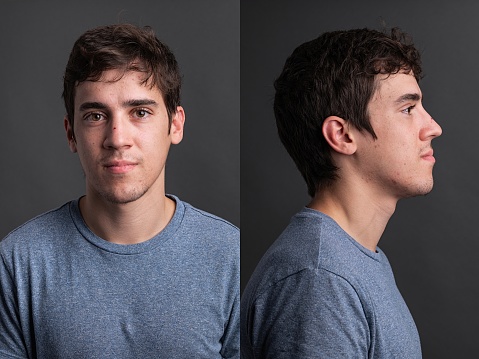 Serious caucasian young man front and profile mugshots on gray background
