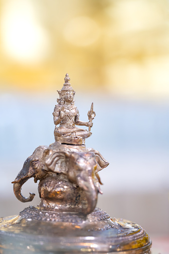 Deity of God Indra is riding Erawan (Airavata) three head elephant, the Bronze Statue on yellow and pastel shade background.