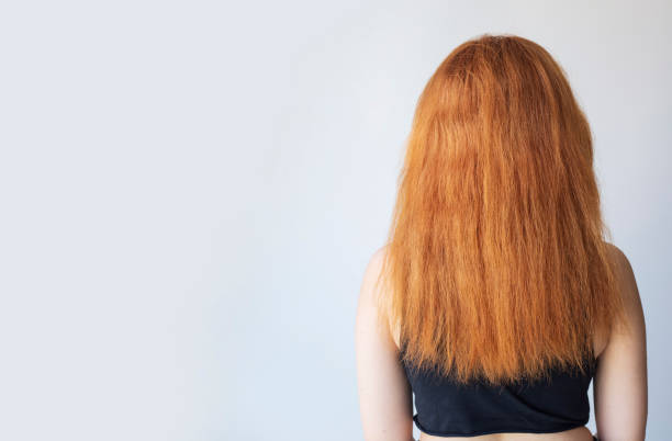 istock Back view of upset woman with dry damaged hair problem with plain background. Copy space. 1335127798