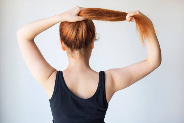 istock Back view of upset woman with dry damaged hair problem with plain background. 1335127973