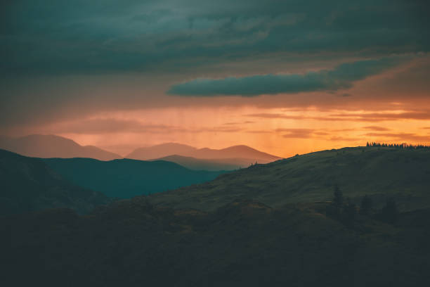 Atmospheric landscape with silhouettes of mountains with trees on background of orange dawn sky. Colorful nature scenery with sunset or sunrise. Sundown paysage in vintage colors and faded tones. Atmospheric landscape with silhouettes of mountains with trees on background of orange dawn sky. Colorful nature scenery with sunset or sunrise. Sundown paysage in vintage colors and faded tones. altai republic photos stock pictures, royalty-free photos & images