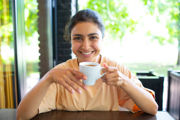 istock Smiling lovely young woman drinking coffee outside 1335130877