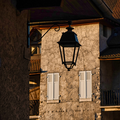 Talloires, France - September 08 2020 : a lantern is hanging in silhouette in an old medieval small french town