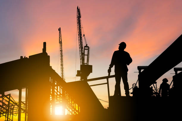 silhouette di ingegnere e operaio in cantiere, cantiere al tramonto la sera - factory site foto e immagini stock