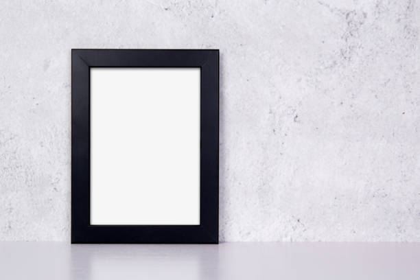 istock Mockup black frame vertical on table top and wall at home, mock up poster for presentation on desk, your design for gallery photo and picture image, border template and decoration for advertising. 1335149049