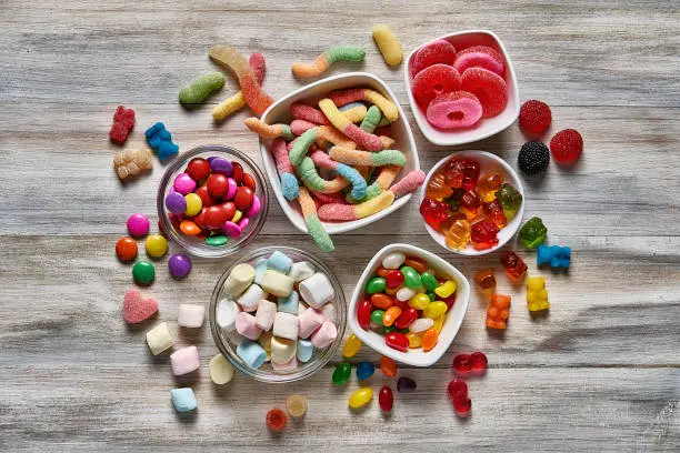 Top view of an assortment of colorful jellybeans, lollipops, candies and marshmallows with copy space