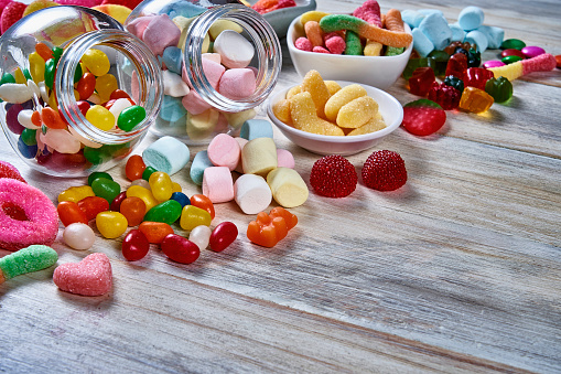 High angle view of an assortment of colorful jellybeans, lollipops, candies and marshmallows with copy space