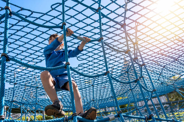 istock Little boy playing at the playground walking on a big rope net 1335156266