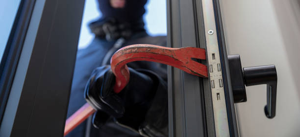 Thief in balaclava holding a crowbar to break a glass window. Masked housebreaker entering a house for stealing in the daytime. Thief in balaclava holding a crowbar to break a glass window. door lever stock pictures, royalty-free photos & images