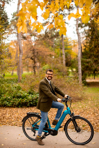 istock Young man with electric bicycle in the autumn park 1335160601
