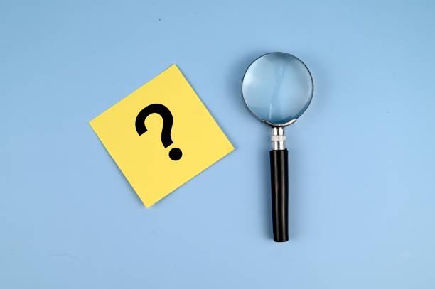 istock Question mark on memo paper with a magnifying glass on blue background 1335169239