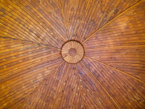 The texture of a spacious wooden dome made of painted boards is viewed from the bottom up.