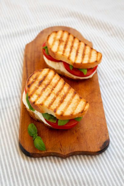istock Tasty Grilled Caprese Panini (Mozzarella, Tomatoes and Basil) on a rustic wooden board, low angle view. 1335176524