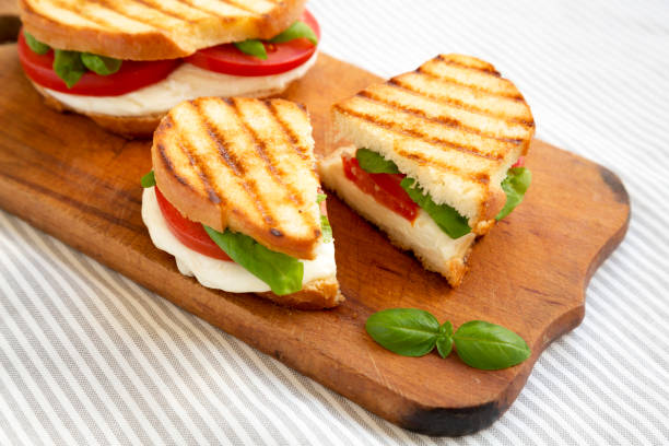 istock Tasty Grilled Caprese Panini (Mozzarella, Tomatoes and Basil) on a rustic wooden board, low angle view. 1335176730