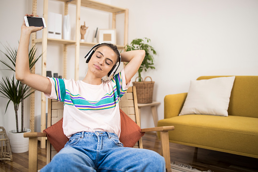 Young woman listening to the music, dancing and enjoying at home.