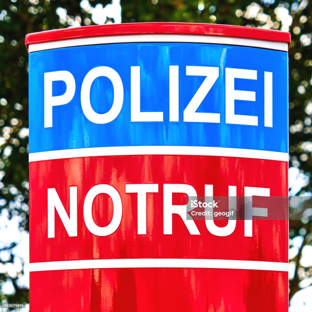 Upper part of red and blue colored emergency call pillar with German inscription Notruf und Polizei (emergency call and police) A Helping Hand Stock Photo