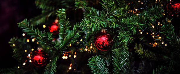 istock Green pine branches with red ornaments and ferry lights 1335180401