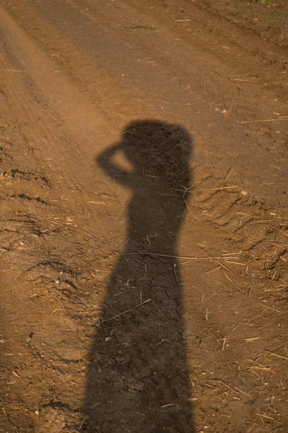 A female shadow on the ground in a field where the harvest was reaped