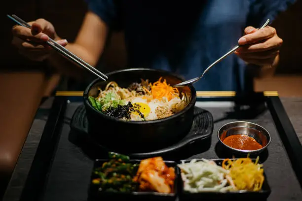 Image of an Asian woman eating bibimbap in Korean restaurant