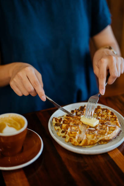 istock Young woman eating waffle and having coffee break in cafe 1335187977
