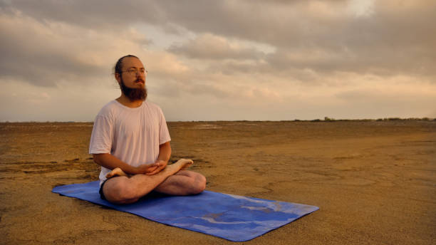 istock Man sits in lotus position at beach 1335189461