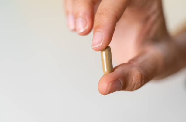Close up hand with herb capsule on white background. Microdosing concept. Psychedelics therapy. Depression, anxiety treatment Close up hand with herb capsule on white background. Microdosing concept. Psychedelics therapy. Depression, anxiety treatment . High quality photo lsd trip stock pictures, royalty-free photos & images