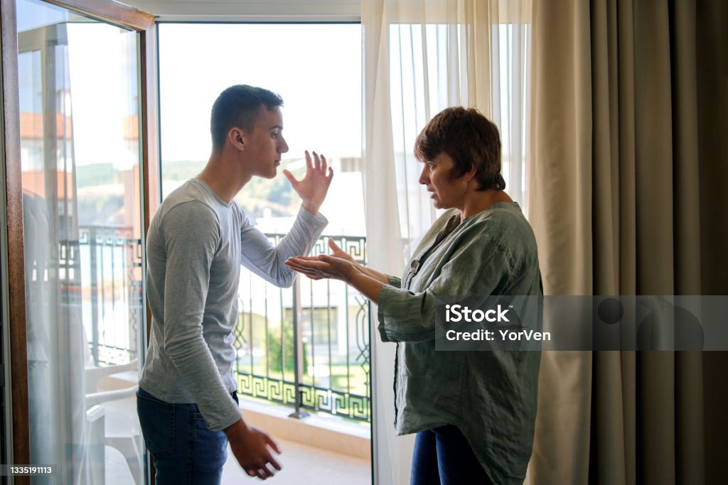 Mother and her teenage son arguing at home Mother Arguing With Teenage Son At Home Mother Stock Photo