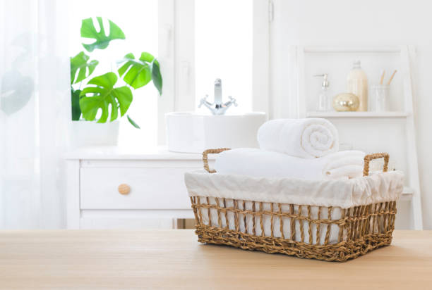 Towels in wicker basket on table with bathroom windowsill background stock photo