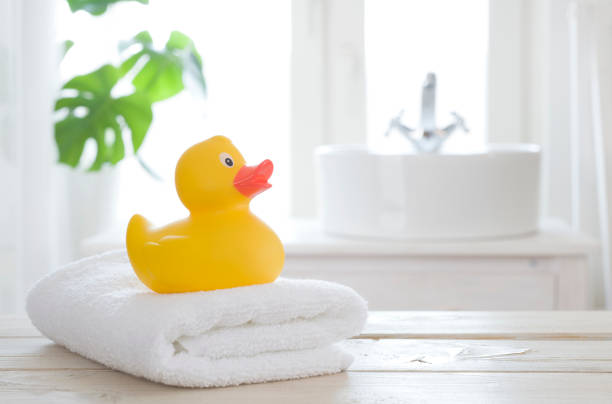 asciugamano e anatra da bagno sul tavolo su sfondo bagno sfocato - rubber duck foto e immagini stock