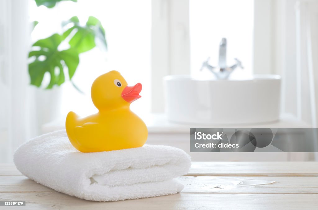 Towel and bath duck on table on blurred bathroom background Duck - Bird Stock Photo