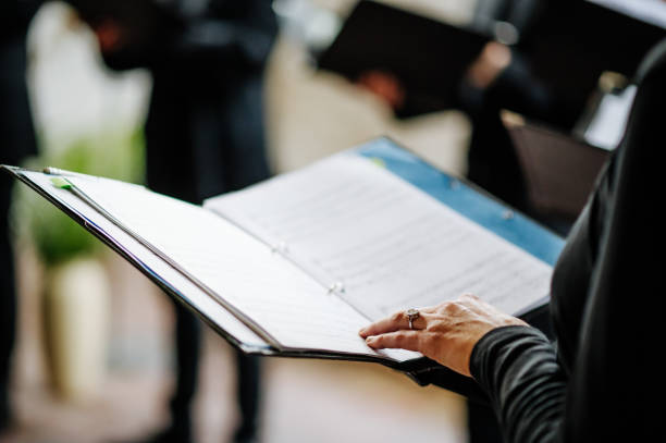 Hand holds notes during choir rehearsal and scrolls, shallow depth of field stock photo