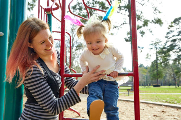 Kid girl and mother playing playground ladder Kid girl and mother playing with playground ladder in the park girl climbing ladder stock pictures, royalty-free photos & images
