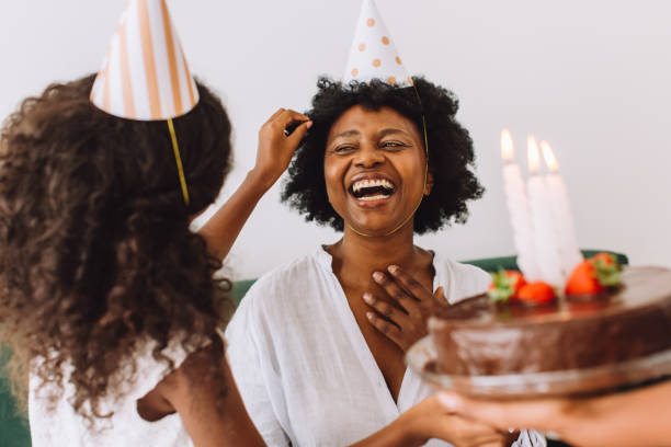 mujer alegre celebrando su cumpleaños con su hija en casa - birthday party adult women fotografías e imágenes de stock