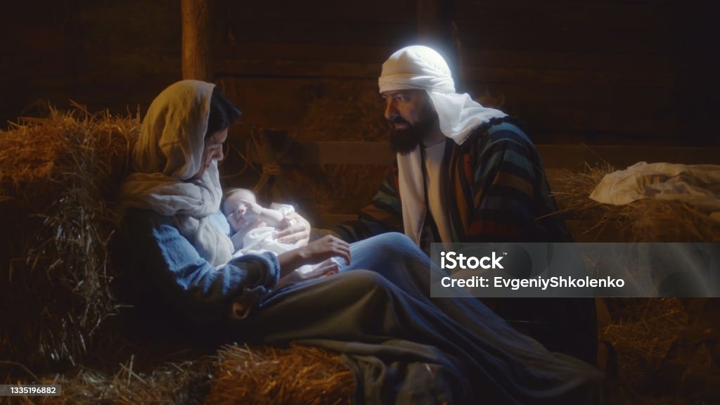 Joseph speaking with Mary after birth of Jesus Joseph talking with Mother Mary caressing baby Jesus on Christmas day in dark stable in Bethlehem Virgin Mary Stock Photo
