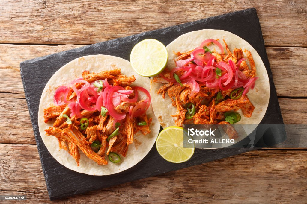 Yucatan Braised Pulled Pork Cochinita Pibil with tortilla and marinated onion closeup in the slate board. Horizontal top view Yucatan Braised Pulled Pork Cochinita Pibil with tortilla and marinated onion closeup in the slate board on the table. Horizontal top view above Pulled Pork Stock Photo