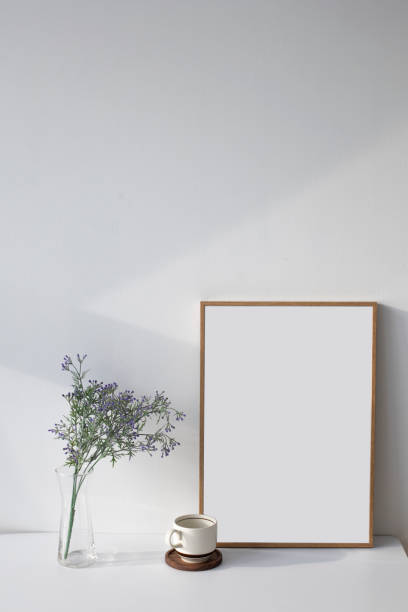 istock Wooden empty picture frame and flowers on white wall. 1335202478