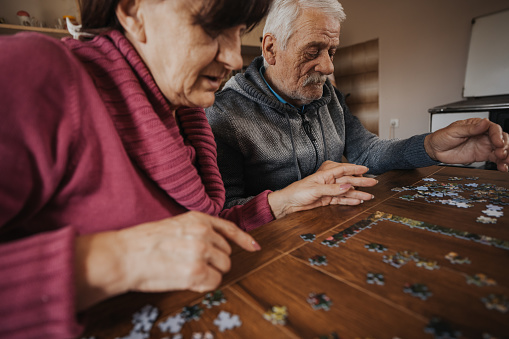 Senior couple having fun while doing a jigsaw puzzle at home