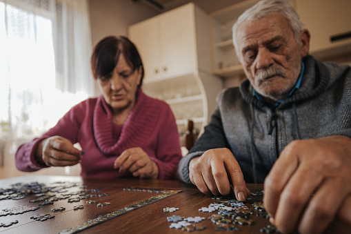Senior couple having fun while doing a jigsaw puzzle at home