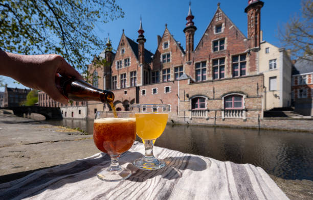 ベルギー・ブルージュの中世の家や運河を望むオープンカフェやビストロテラスでのベルギービールの試飲 - belgium ストックフォトと画像