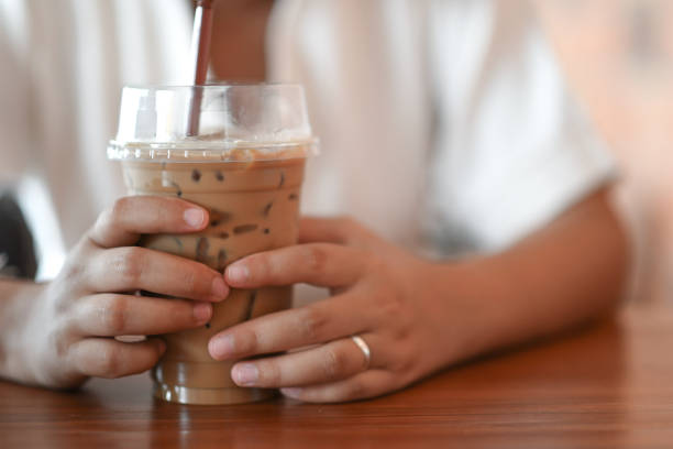 una mujer tomando café helado con ambas manos en la cafetería. - espresso coffee cream coffee shop fotografías e imágenes de stock