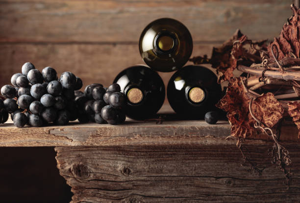 garrafas de vinho tinto com uvas e videira seca em uma velha mesa de madeira. - port wine madeira wine bottle vine - fotografias e filmes do acervo