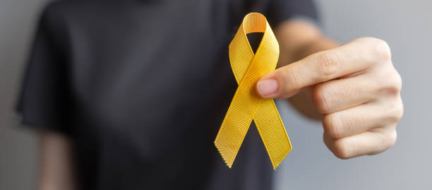 suicide prevention day, sarcoma, bone, bladder and childhood cancer awareness month, yellow ribbon for supporting people living and illness. children healthcare and world cancer day concept - amarelo imagens e fotografias de stock