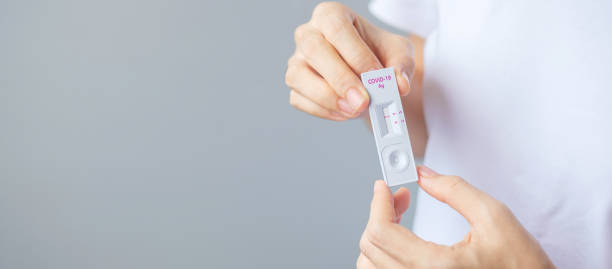 istock man holding Rapid Antigen Test kit with Negative result during swab COVID-19 testing. Coronavirus Self nasal or Home test, Lockdown and Home Isolation concept 1335212737