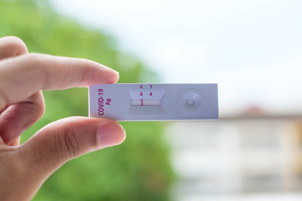 istock man holding Rapid Antigen Test kit with Negative result during swab COVID-19 testing. Coronavirus Self nasal or Home test, Lockdown and Home Isolation concept 1335213478