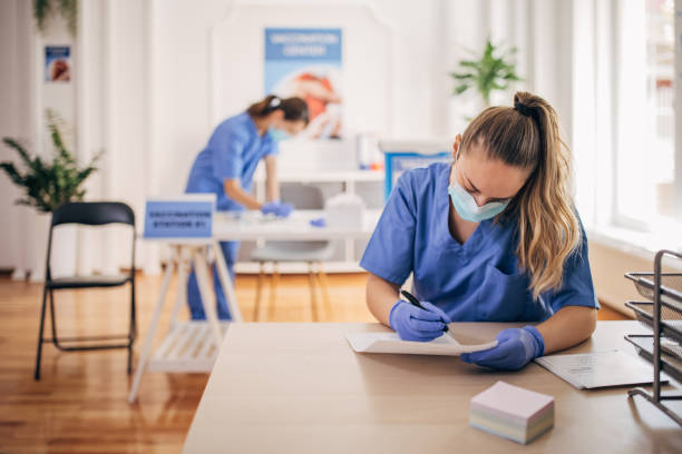 Medical workers at vaccination center Two people, female medical workers working in covid vaccination center. herd immunity photos stock pictures, royalty-free photos & images
