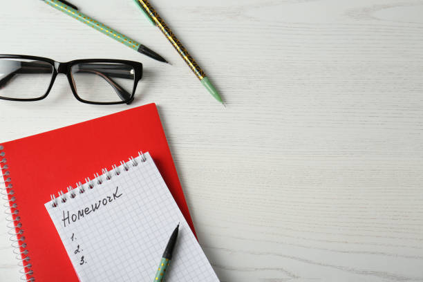 istock Flat lay composition of notebook with word HOMEWORK on white wooden table. Space for text 1335215630